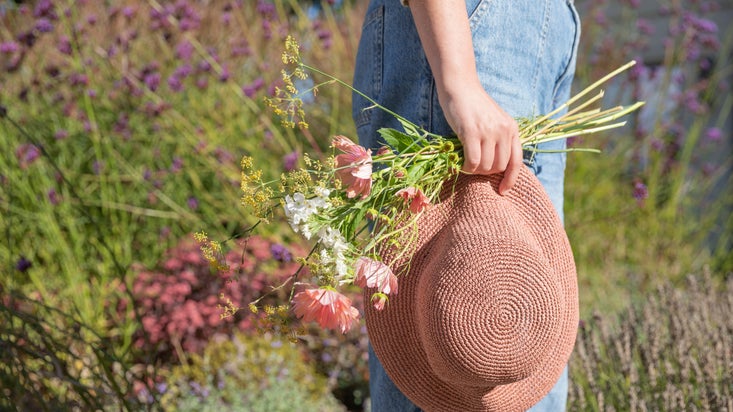 A hand holding a fabric hat and mixed flowers